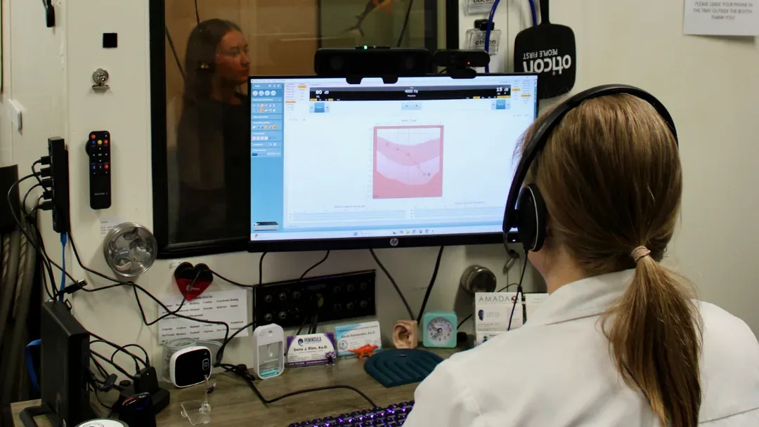 Doctor of Audiology conducting a hearing evaluation in a sound booth
