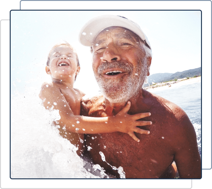 grandfather holding child in the water smiling with custom ear plugs